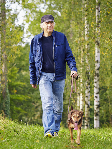Dog walking on a lead in grass with owner